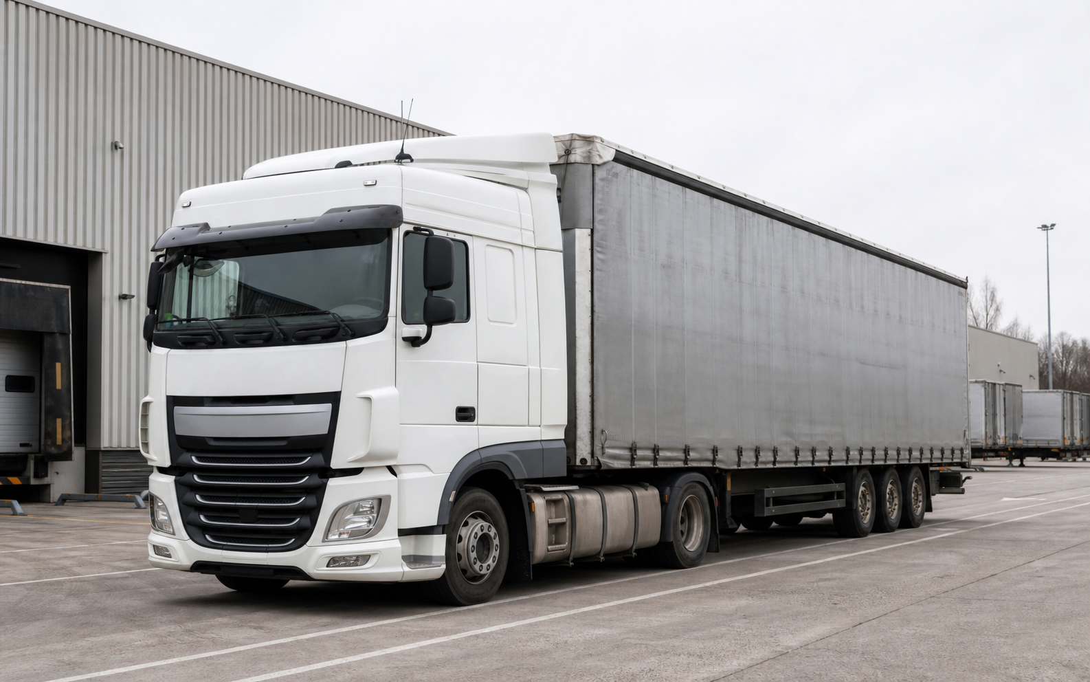 Trekker met curtain-side oplegger op logistiek terrein